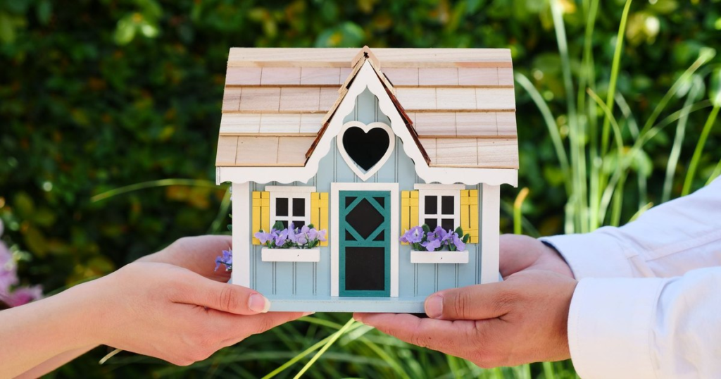 Two people holding a small model house, representing protecting a home with the right insurance