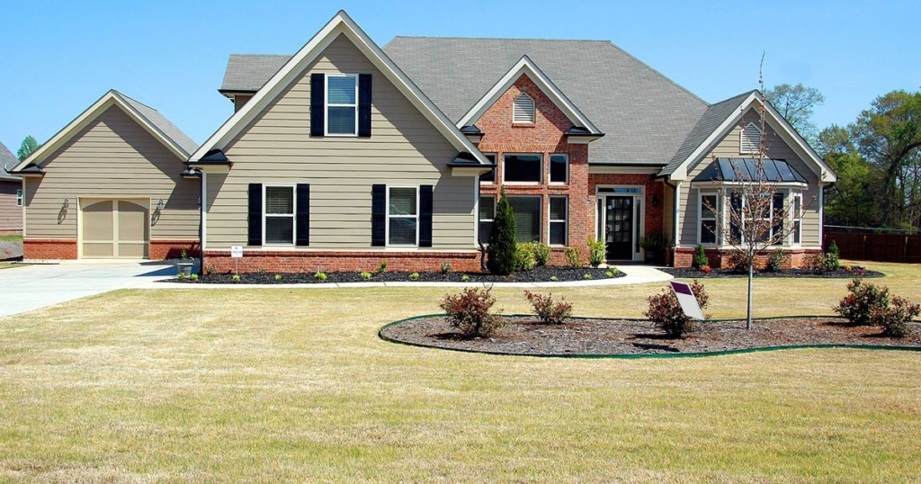 Brick and siding single-story home with a wide front lawn under a clear blue sky